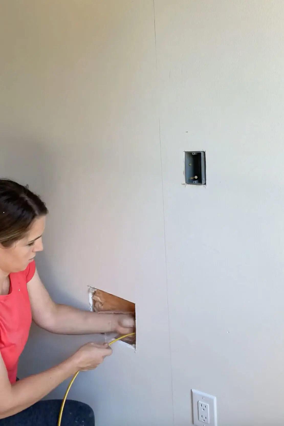 Running electrical wiring through the wall to prepare for installing a fireplace insert.